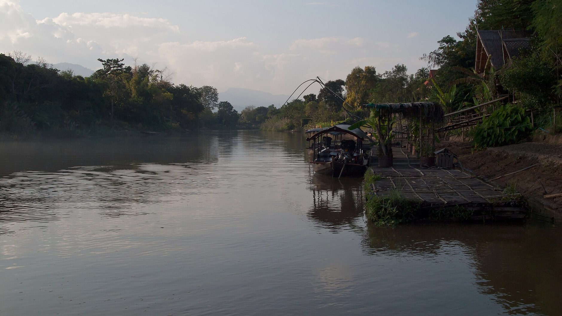 The Ping River north of Chiang Mai in soft evening light, with a moored boat and forested banks (illustrative photo)